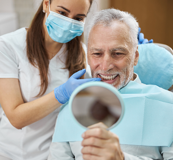 Man in dental chair checking smile in mirror