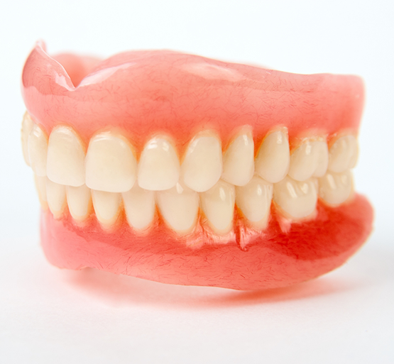 Close up of dentures sitting on white background