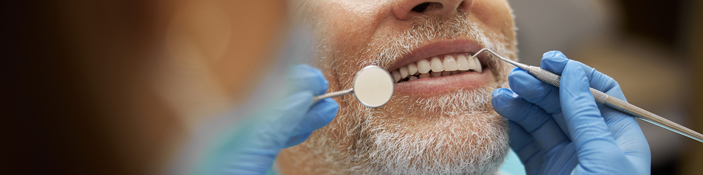 Close up of man's smile being examined with dental instruments