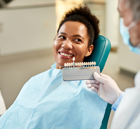Woman in dental chair having teeth shade matched for veneers