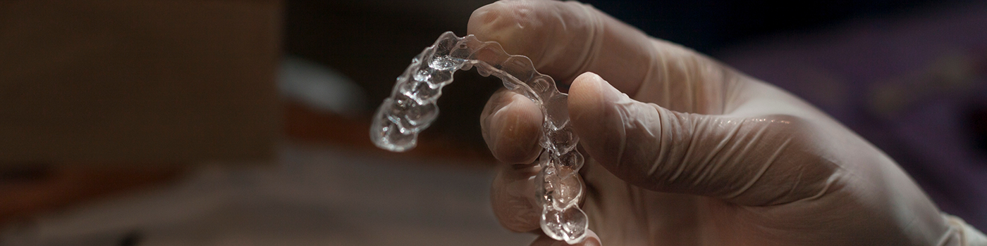 Close up of hand holding SureSmile clear aligners in Haverhill