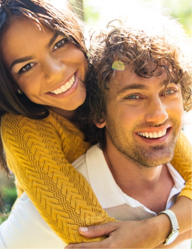 Smiling man giving smiling woman a piggyback ride